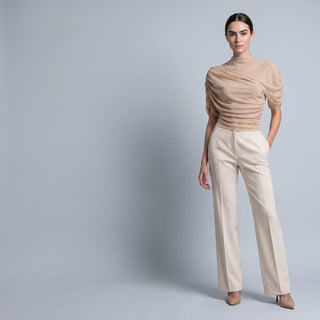 Woman in a draped blush top and cream tailored trousers