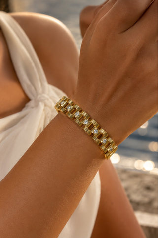 Like Watch Band in gold, worn on the wrist over a white halter top