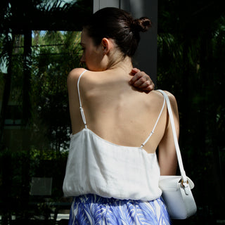 Mystra Silk Crop Top in white, back view with low scoop back, worn with a white shoulder bag