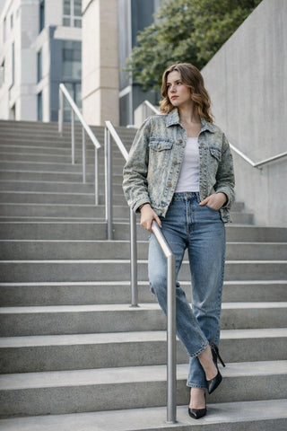 Woman in a light denim jacket and jeans walking down concrete city steps